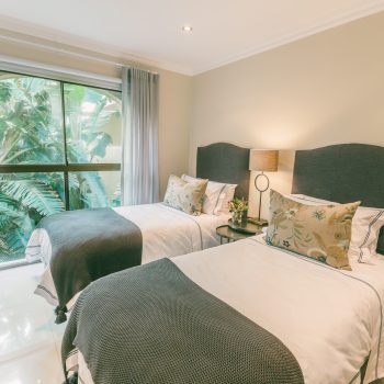 Sweep open the curtains of this splendid twin guest bedroom to take in the lush, leafy garden below.