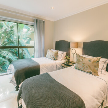 Sweep open the curtains of this splendid twin guest bedroom to take in the lush, leafy garden below.